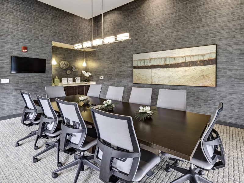 This image shows the door view of the conference room that features sophisticated chairs, tables, and lights.