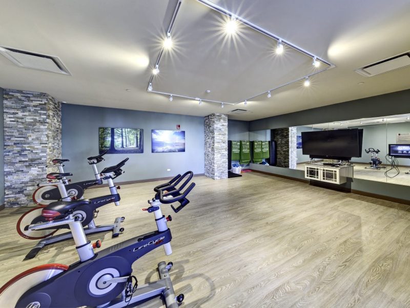 This image shows an expansive view of the fitness gym equipment featuring the yoga and spin studio with indoor cycling mirror that was ideal for flexibility and strength exercise.