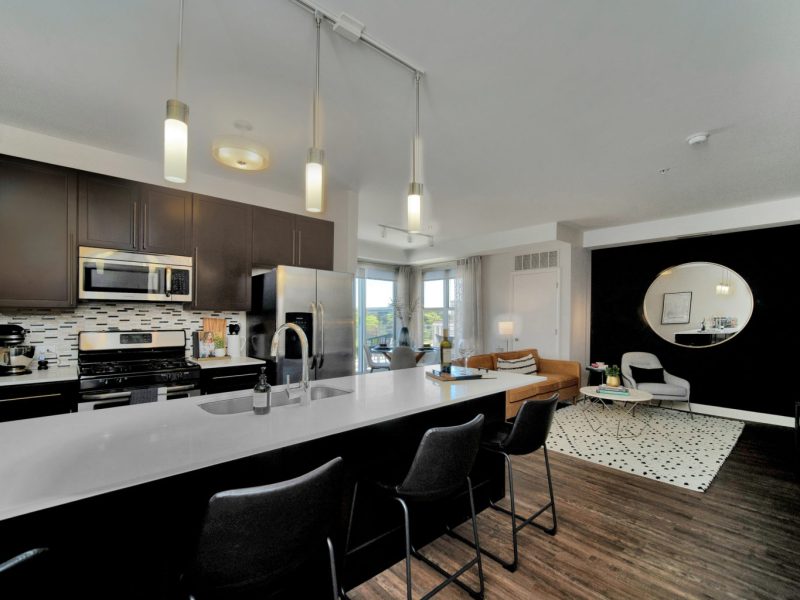 This image shows the Premium Apartment Feature, especially the kitchen island showcasing a granite-inspired countertop, a neat design, stainless-steel appliances, and built-in microwaves.