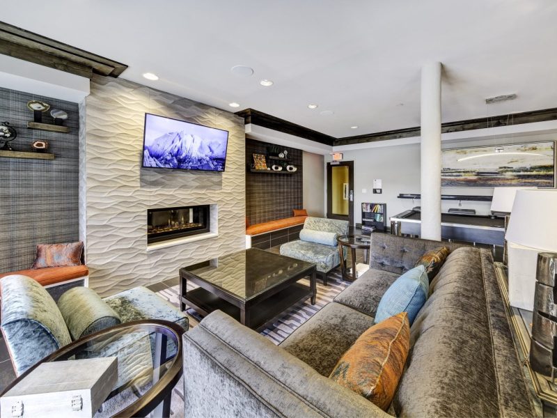 This image shows the resident lounge area with a flat-screen TV, fireplace, and comfortable pillows.